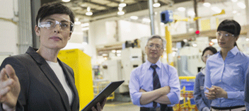 Three business people wearing safety goggles in production facility