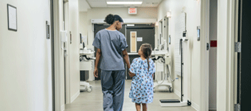 Nurse and child patient waking down hospital corridor 
