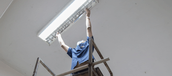 Worker on platform installing overhead lighting
