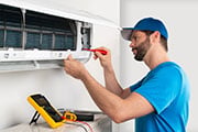 Image of a man using tools on an appliance within a home.