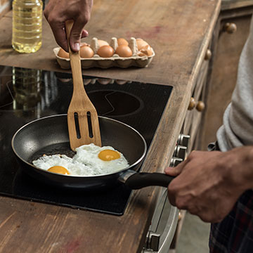 Two eggs cooking in a frying pan on an induction stovetop.