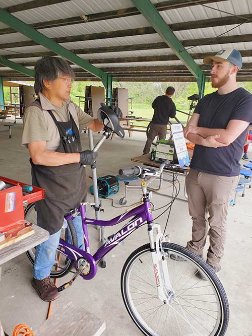 Volunteer in an apron repairing a bike.