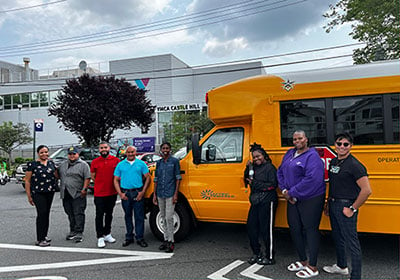 Team standing in front of a school bus holding an award.