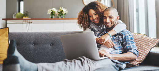 couple on couch looking at laptop