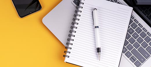 Notebook and pen lying on a laptop computer
