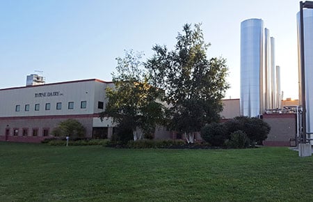 Front of the Byrne Dairy building with green grass in front and blue sky above.