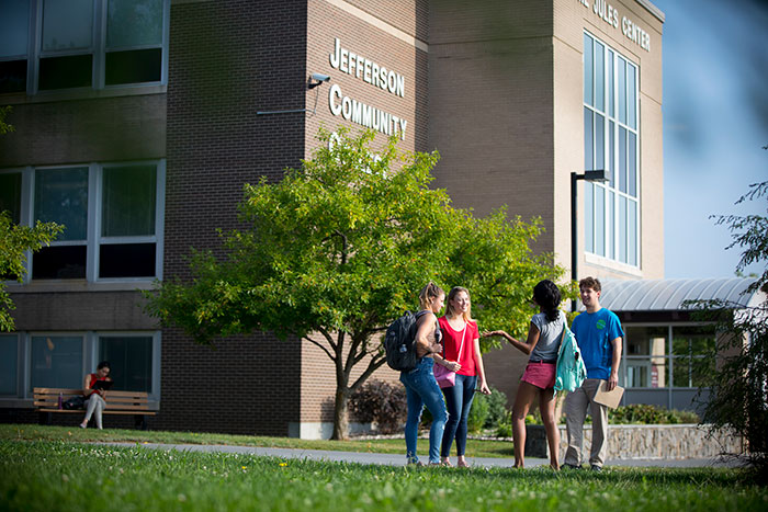 Group of students standing and talking in front of a Jefferson Community College building.