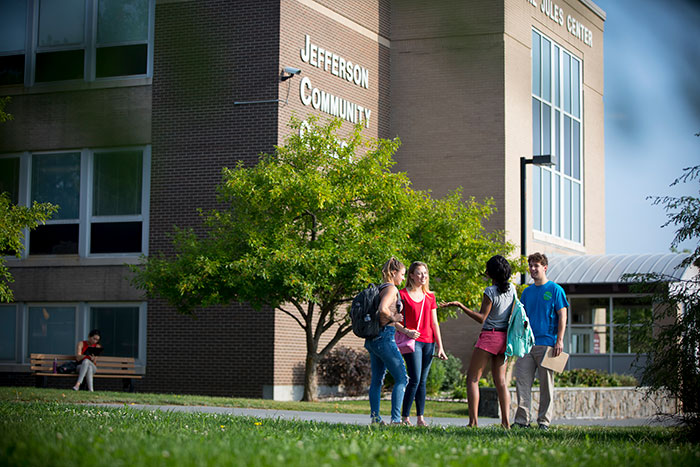 En gruppe studerende, der står og taler foran en Jefferson Community College-bygning.