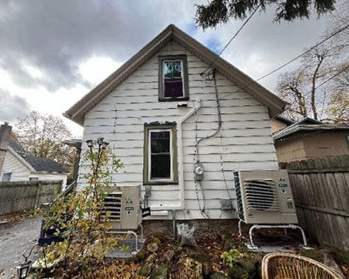 Back of house with two heat pump units.