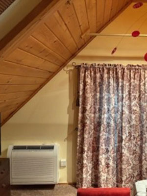 Second heat pump until installed next to window in second floor room with a-frame ceiling.