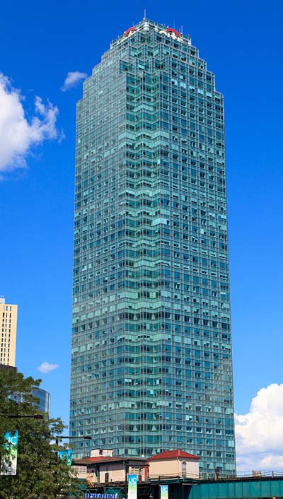 Street view of One Court Square, a 53-story building with blue sky in the background.
