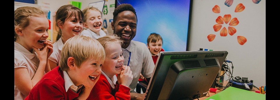 teacher and students looking at computer