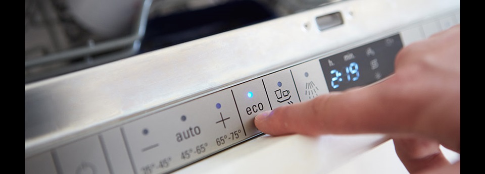 Close-up of an appliance's control panel and someone pressing the "eco" button.