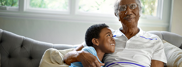 Grandfather and grandson sitting on a couch, smiling