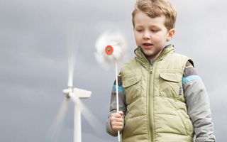 Boy with pinwheel in from of windmill