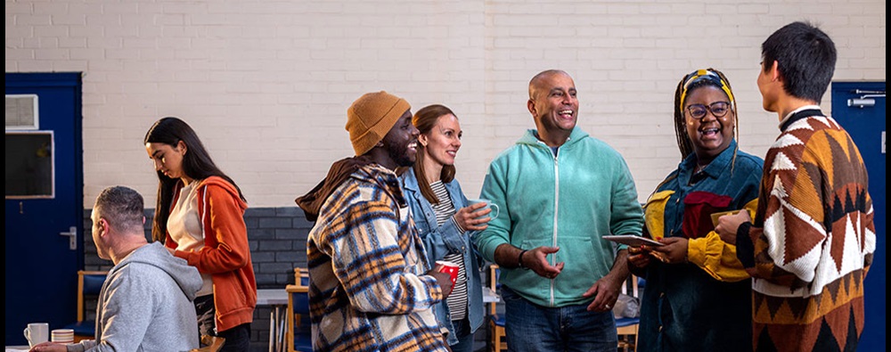 Diverse group of people standing in a discussion circle smiling.