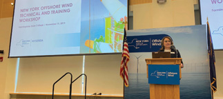Speaker at podium in front of presentation screen for offshore wind event