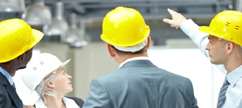 Business people in suits with hard hats looking over interior space and pointing