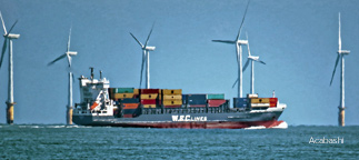Cargo ship traveling past offshore wind turbines